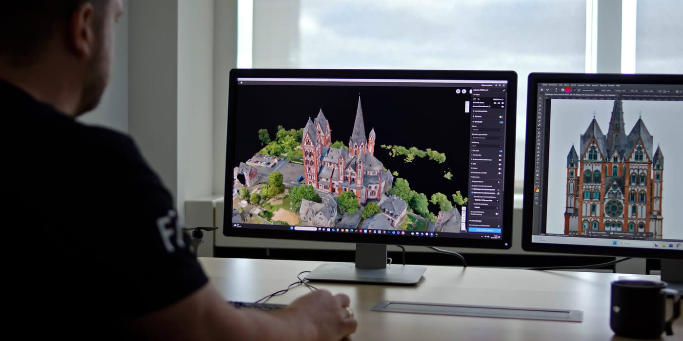 Analyst reviewing a 3D photogrammetry model of a building complex on a monitor