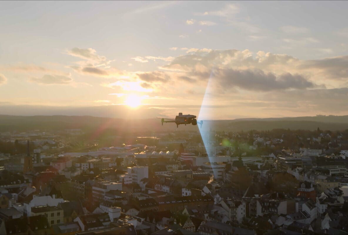 DJI Matrice-series drone flying above city rooftops at sunset