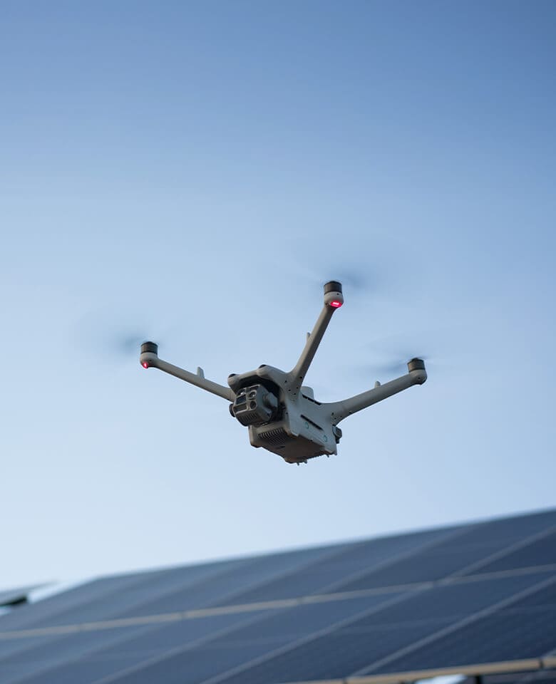DJI Matrice 4D-series aircraft in flight against a blue sky above solar panels